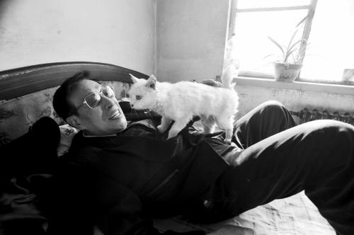 Pan is playing with his pet cat Mimi at their home in Shenyang, Liaoning province. (Photo source: Shenyang Evening News)