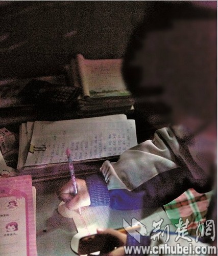 The girl uses a cellphone light to do her homework. [Photo: cnhubei.com]
