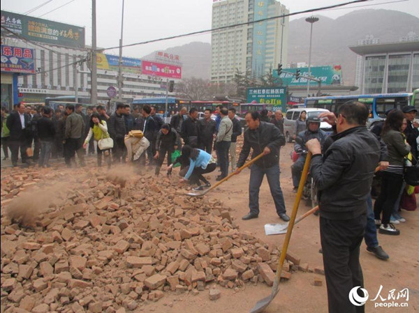 Police officers and residents are clearing bricks away from roads. (Photo source: people.cn)