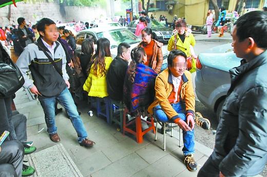 Couples sit on stools waiting in a line outside a maternity hospital in Chongqing Municipality on March 31, 2014, all to consult doctors about test-tube babies.