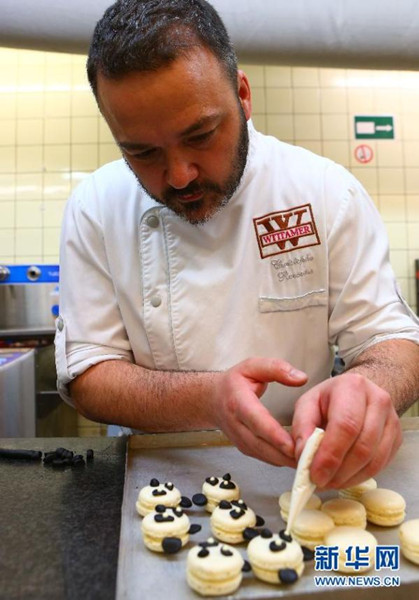 A baker of Wittamer & Co is making Pandarons, a kind of panda-themed Macarons offered to observe the arrival of two Chinese panda ambassadors in Belgium. (Photo source: xinhuanet.com)