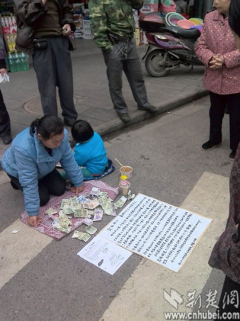 Liu Xiaoying kneels near a food market in Xinzhou district and kowtows to passersby for help. (Photo: cnhubei.com)