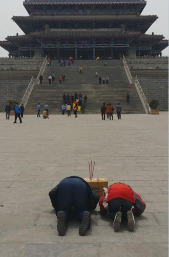 The civil servant and his daughter kowtow to the Guanque Tower for career promotion. (Photo source: China National Radio) 