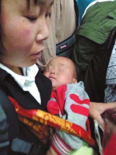 A photo of a woman holding a sleeping baby and begging on Beijing Metro Line 10 made the rounds on Chinas popular social networking sites. [Photo: the Beijing Times]