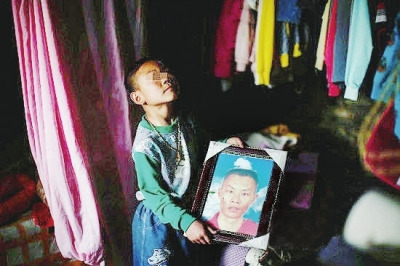 Wang Guangrong's son holds the portrait of his deseased father. [dnkb.com.cn]