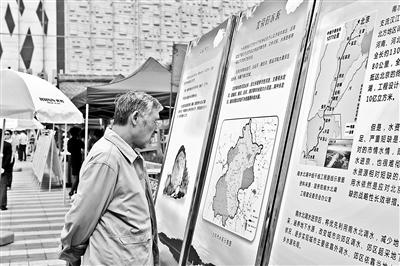 A campaign designed to increase residents water-saving awareness has been launched in Beijing on Sunday. The picture shows a man is reading water resources information on a display board. (Photo source: Beijing Youth Daily)
