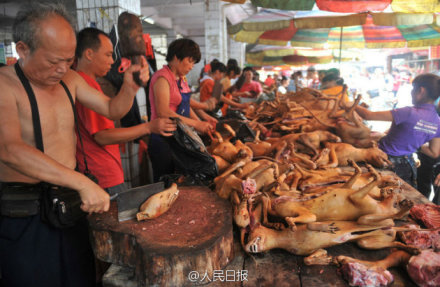 The undated photo shows a man is cutting dog meat at a stall in Yulin, Guangxi. [Photo: the official Sina Weibo account of People’s Daily]