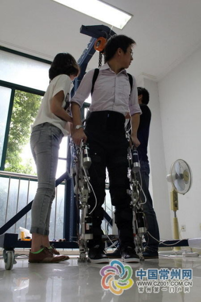 Staff help Chen to wear the robot exoskeleton suit.[Photo: cz001.com.cn]