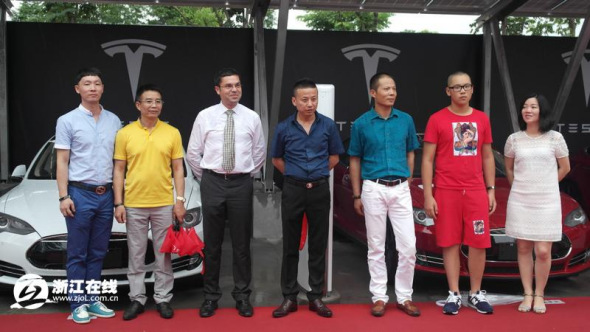 Jerome Guillen, Teslas vice president of worldwide sales and service, and customers in Hangzhou pose for photos on July 24, 2014. [Photo: Zjol.com.cn]