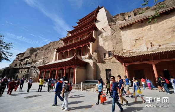 Tourists visit the Mogao Grottoes on August 31, 2014. [Photo: Xinhunet / Chen Bin]