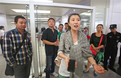 A female passenger of China United Airlines flight KN5216 tells the story of some people smoking onboard by a luggage carousel at Beijing Nanyuan Airport on Sunday, August 31. (Photo: the Beijing News) 