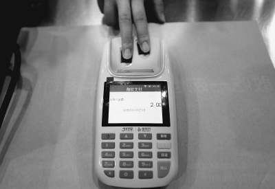 A customer pays for a Coke by scanning fingerprints at Funiutang restaurant, the first restaurant in Beijing to adopt fingerprint payment, on Sept.2, 2014. (Photo: Beijing Daily)