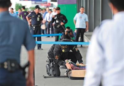 A Philippine policeman checks some unclaimed luggage at the entrance of Terminal 3 of the Manila International Airport on Sept. 1, 2014. (Photo: the Beijing News)