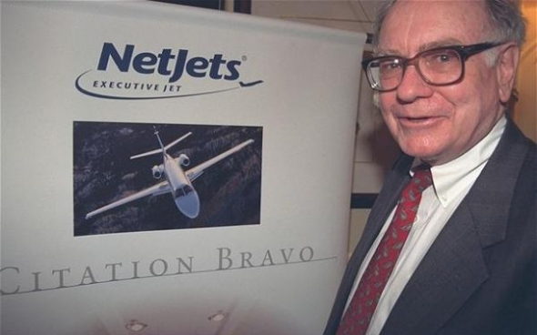 Warren Buffett stands beside the logo of NetJets Business Aviation. (Photo: China Daily)