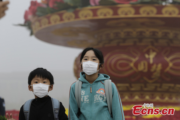 File photo shows children wear face masks on a smoggy day in Beijing. (Photo/China News Service)