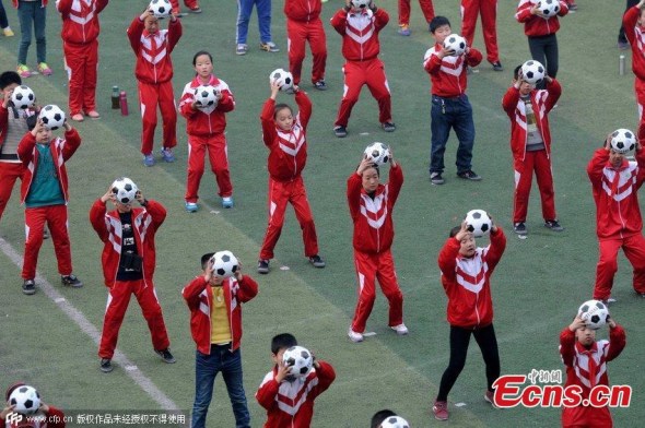 Elementary students carry footballs during an exercise at a school in Luoyang, Central China��s Henan province, March 16, 2015. Local teachers choreographed the exercise sets to increase interest in playing football. China has unveiled a football reform plan to boost the development of the game in the country. (Photo/CFP) 