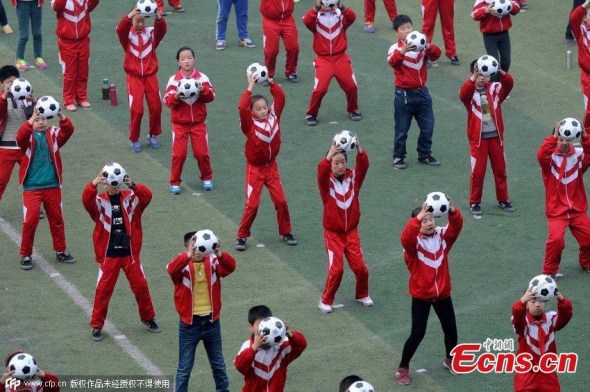 Elementary students carry footballs during an exercise at a school in Luoyang, Central Chinas Henan province, March 16, 2015. Local teachers choreographed the exercise sets to increase interest in playing football. China has unveiled a football reform plan to boost the development of the game in the country. (Photo/CFP) 