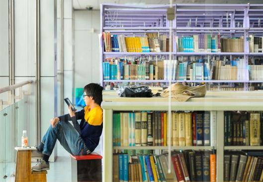 A young man reads novels on a Kindle at a library in Shanghai. The rise of e-reading is challenging the traditional way of reading books. (File photo/ Xinhua)