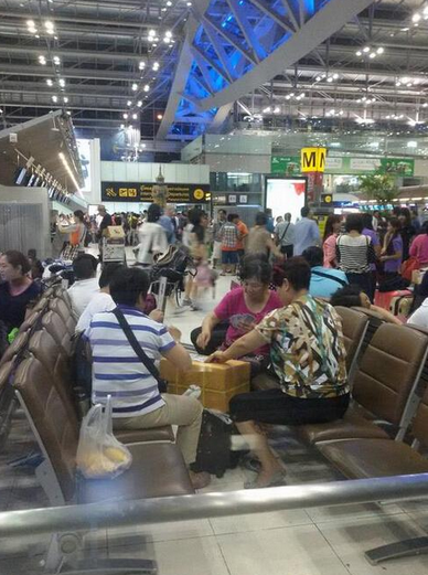 A group of middle-aged Chinese women play cards on a box at Bangkok International Suvarnabhumi Airport. 