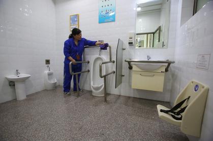 A janitor cleans the facilities at a unisex toilet on Yan'an Road yesterday, one of the city's first. (Photo: Shanghai Daily/Wang Rongjiang)