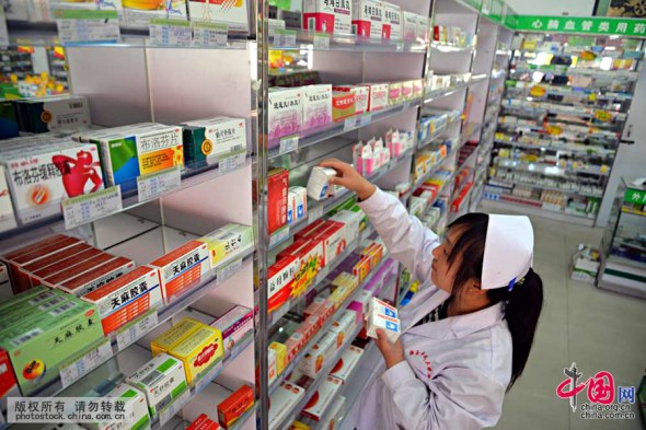 A stuff memeber checks medicines on the shelves in a drug store in Shandong province, May 5, 2015. (Photo/china.org.cn)