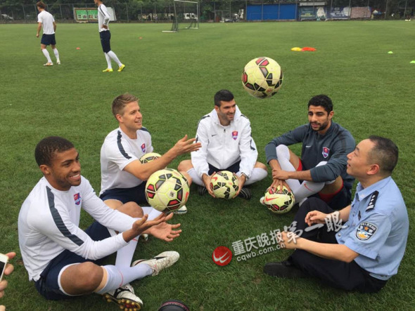 Bai Hua (R), a policeman in Southwest China’s Chongqing municipality, talks with foreigners on a football field, May 6, 2015. (Photo/cqwb.com.cn) 