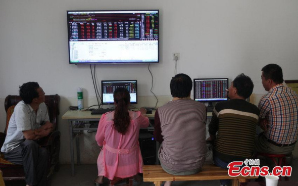 Farmers look at screens showing stock information at a village in Xingping city, North Chinas Shaanxi province, June 1, 2015. (Photo/CFP)