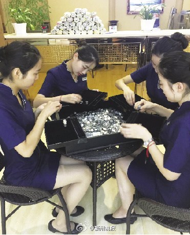 Jewelry store staff in Anhui province calculate coins afforded by a young man in Fuyang city. (Photo/Chinanews.com)