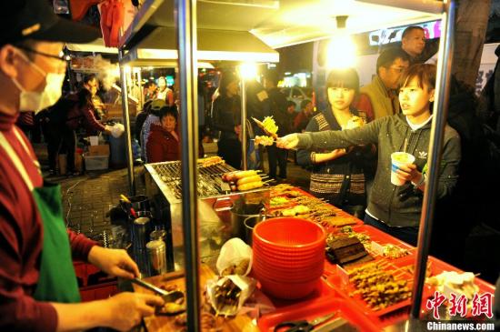 Mainland tourists have a taste of Taiwan snacks at a night fair. (File photo: China News Service/ Wang Dongming) 