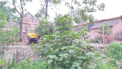 A digging machine stops outside of a house where a WWII bomb left by the Japanese army has killed two and injured another five. (Photo/dahe.cn)