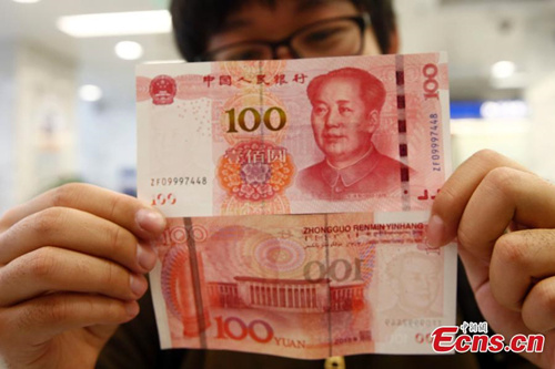 A resident shows new 100-yuan bank notes in a branch of the Bank of Communications in Beijing on November 12, 2015. The new 100-yuan bank note is put into use from Thursday, November 12. (Photo: China News service/ Zhang Hao)