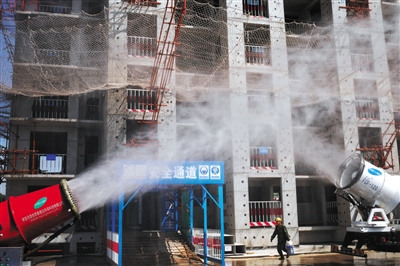 A multi-functional mist-generation machine sprays water over rising dust from a building site in the Chaoyang District's Dongba area, May 10, 2016. (Photo/Beijing News)