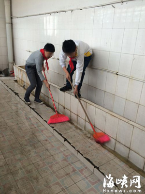 Two students from an elementary school in eastern Fujian Province clean public toilets