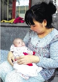 Yang Xiaoqing, mother of a intersex baby , holds the new-born in her arms . (Photo/Zhengzhou Evening News)