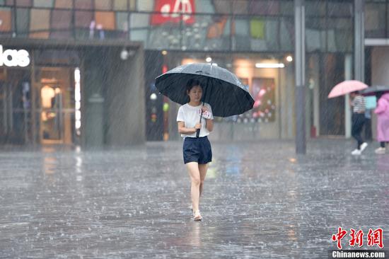 A woman holding an umbrella walks in the rain in Beijing, July 20, 2016. (Photo/Chinanews.com)
