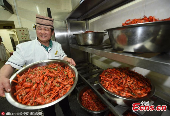 A cook shows off crayfish served up at a canteen in Nanjing University of Aeronautics and Astronautics in Nanjing City, the capital of East Chinas Jiangsu province.(Photo/IC)