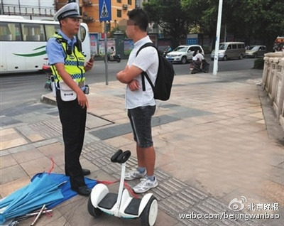 A policeman stops a young self-balancing scooter rider in Beijing. (Photo/Beijing Evening News)