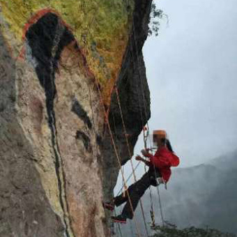 A woman pints a giant portrait on a steep cliff of the 219-meter-high Fanzheng Rock. (Photo/Qianjiang Evenning Nfews)