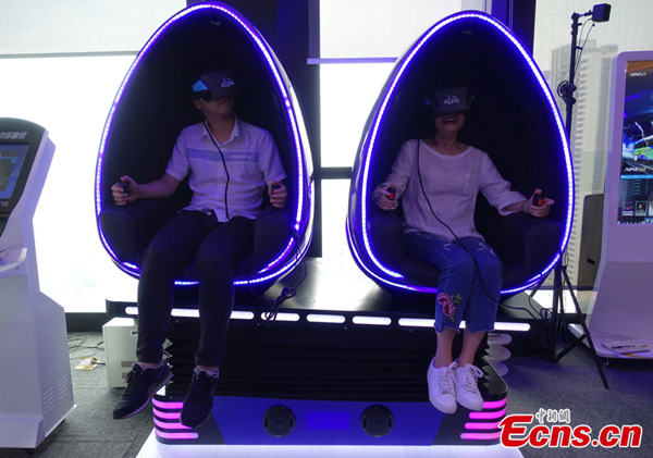 Two media representatives attending the China-Russia Internet Media Forum experience a 9D virtual reality cinema series product manufactured by NINED VR in Tianhe district, Guangzhou, South Chinas Guangdong Province, Oct. 28, 2016. (Photo: Ecns.cn/Wang Fan)