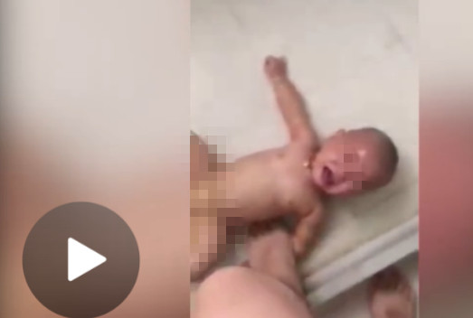 A grab of the video shows the man stepping on the arm of the baby boy who lying on the ground of a bathroom. 