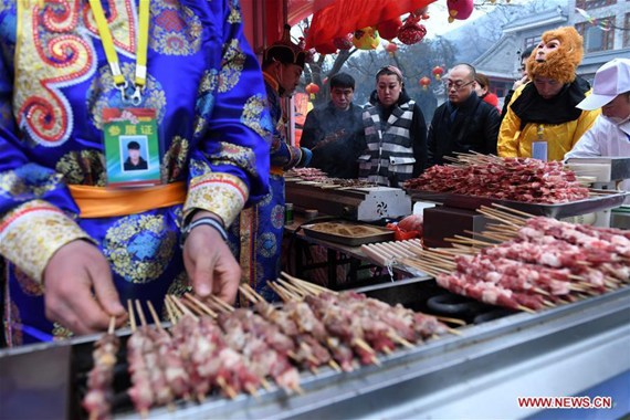 A vendor sells lamb shashlik at a temple fair of the Badachu Park in Beijing, capital of China, Jan. 28, 2017. (Xinhua/Li Jundong)