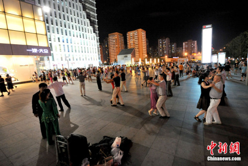 People dance at an open space in front of a building. (File photo/Chinanews.com)