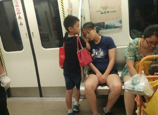 A boy stands beside a handrail as his mother takes a nap with her head supported by his hand. (Photo/Chongqing Morning Post)