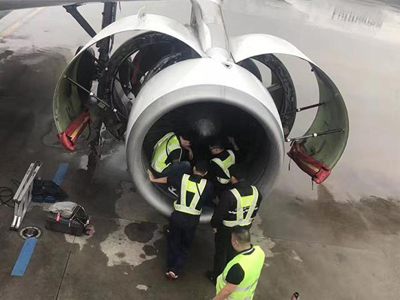 Airport staff check the engine of China Southern Airlines flight CZ380, into which an elderly woman tossed nine coins. (Photo from the Web)