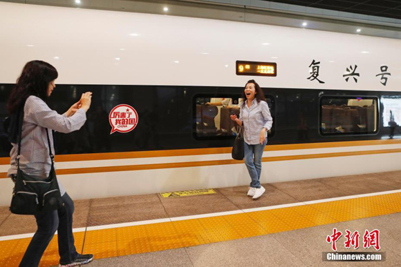 A passenger pose for photo with a Fuxing train at the Hongqiao Railway Station in Shanghai, Sept. 21, 2017. (Photo/China News Service)