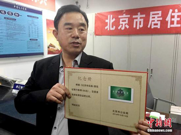 A man shows a Beijing residence permit. (Photo: Chinanews.com/Ma Xueling)