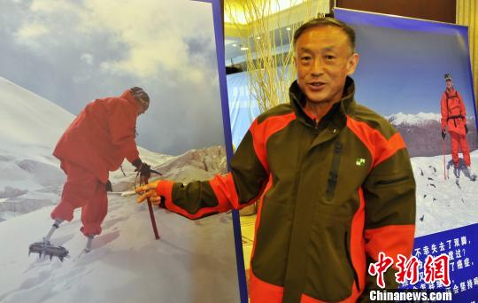 Xia Boyu, 69, points to his photo in which he climbs on the summit of Mount Qomolangma. (Photo/China News Service)