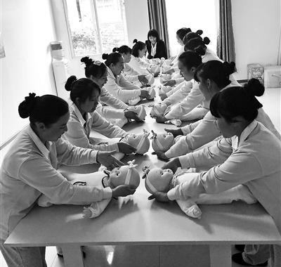 Domestic helpers are trained to take care babies at a company. (Photo/Beijing Youth)