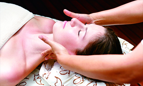 A lady has whitening products massaged into her skin at a beauty parlor. 