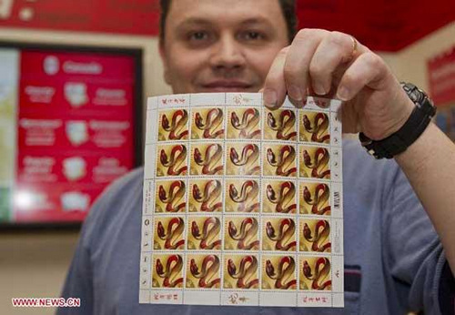 A staff member of Canada Post shows domestic rate stamps of the Year of the Snake at a post office in Toronto, Canada, Jan. 8, 2013. Canada Post issued the Year of the Snake domestic and international rate stamps and collectibles on Tuesday in celebration